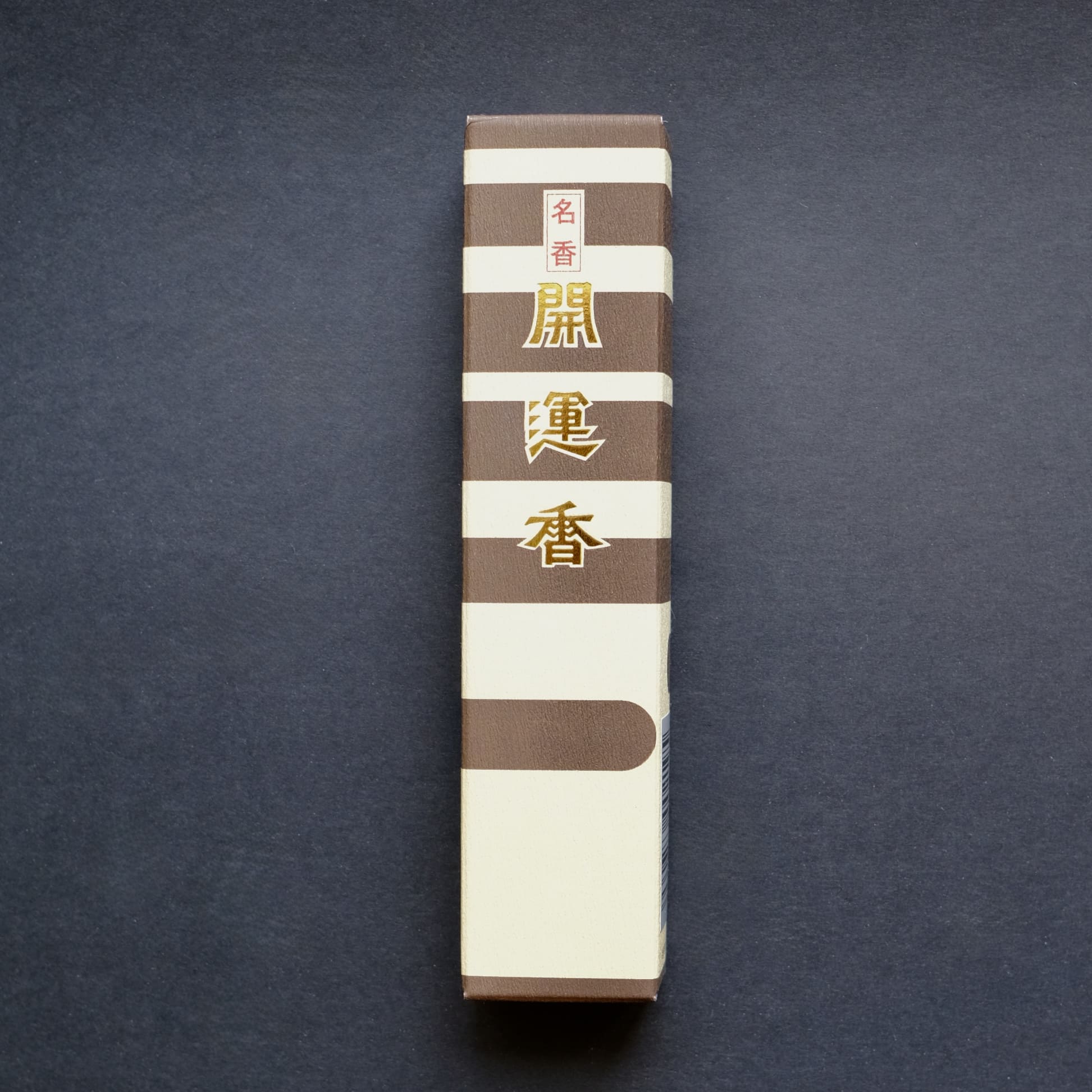 Front of the Baieido Kai Un Koh incense box, featuring brown and cream stripes with the name in gold Japanese characters.