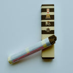 Baieido Kai Un Koh incense box with a bundle of the incense sticks resting in front, partially unwrapped to show the brown sticks inside.
