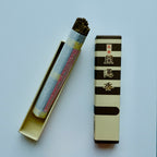 Baieido Kai Un Koh incense with the box opened to show the bundle of sticks in the inner tray, placed next to the striped outer sleeve."