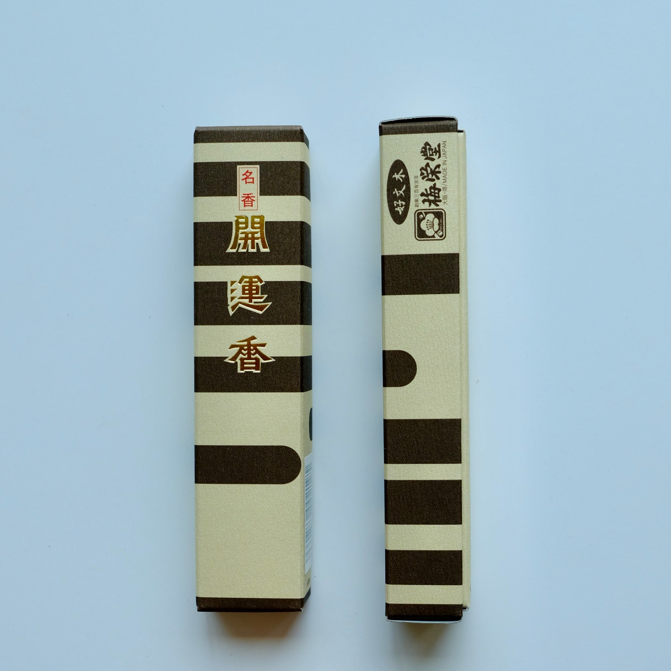 Baieido Kai Un Koh incense with two boxes laying flat, left box showes the front of the pacakge in golden Japanese kanji, placed next to a box showing the side of the package with Baieido Logo.