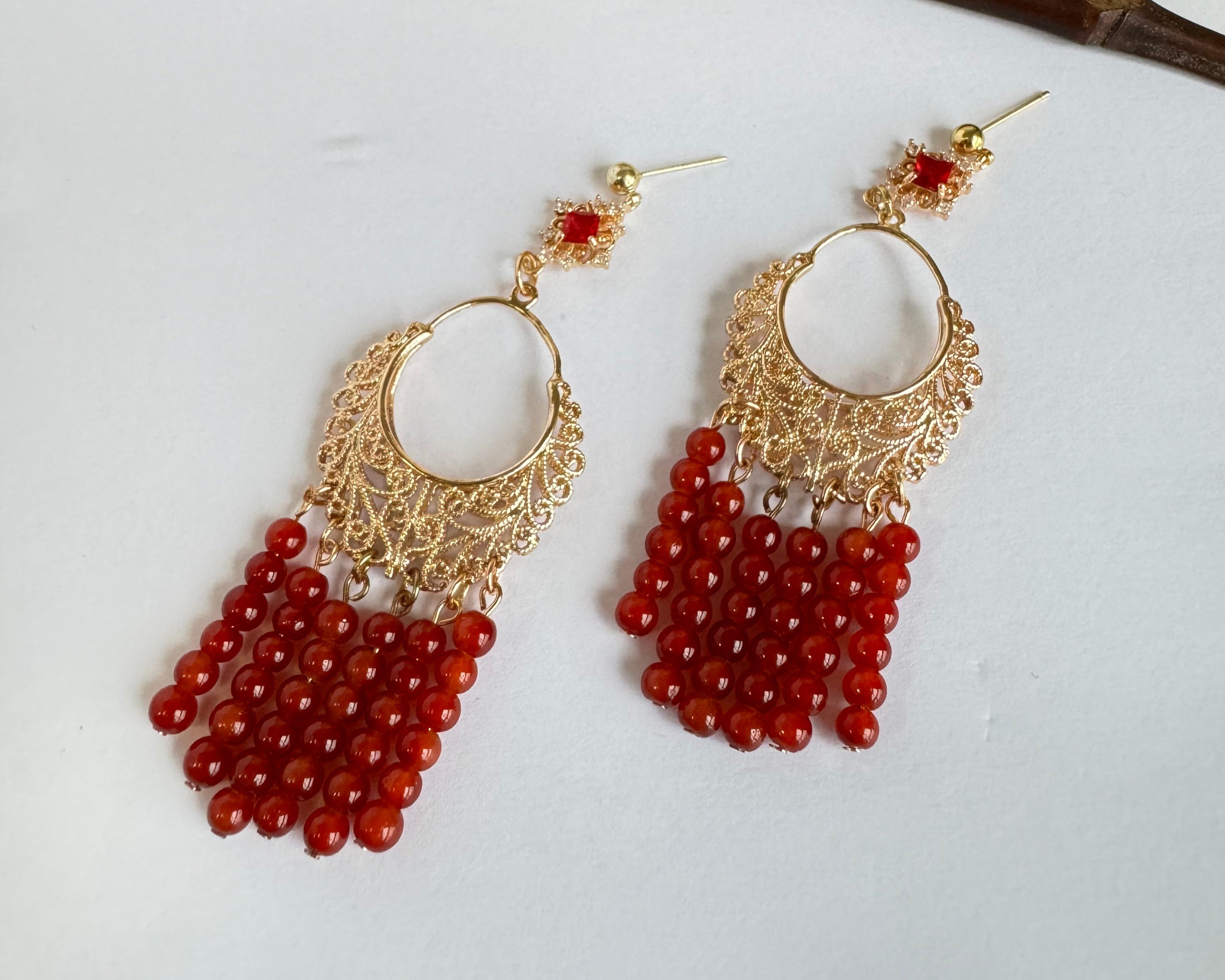 A dangle of red agate beads earrings with golden crescent ring