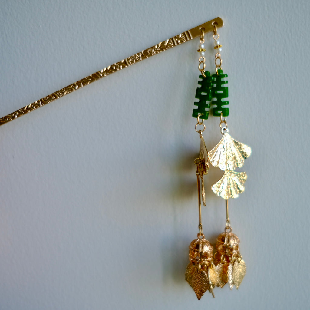 Close up shot of handmade Happiness Duo, Double Happiness(喜) hair pin. Chinese character motif in Jade green, golden color tone, typical Chinese wedding accessories.