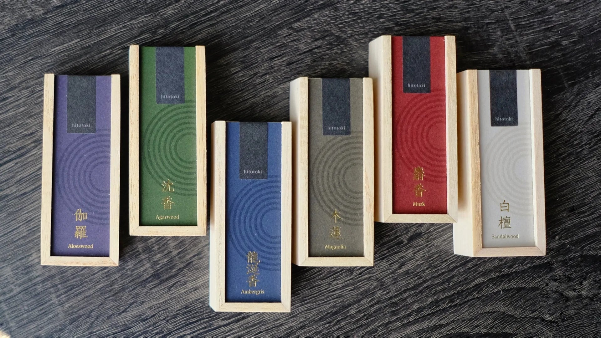 Set of wooden incense boxes with blue and red labels on a dark wooden surface