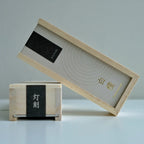 Two wooden incense boxes with black labels on a light gray background