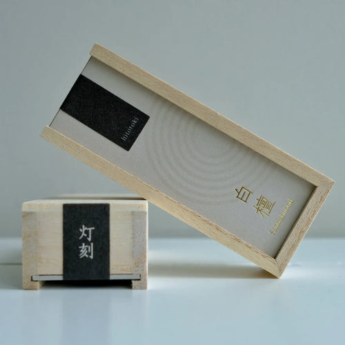 Two wooden incense boxes with black labels on a light gray background