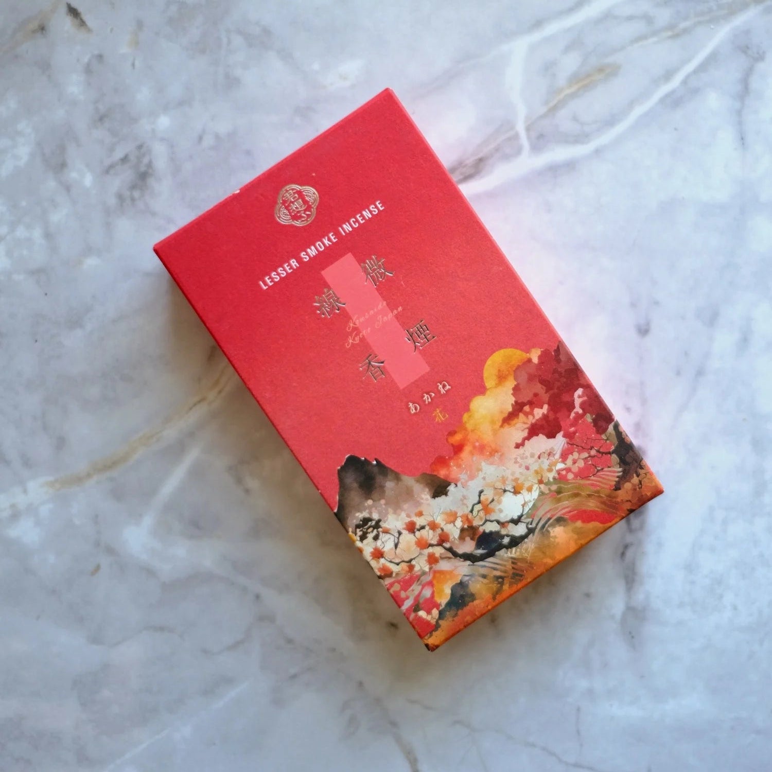 Red box of Kousaido low smoke incense with artistic design on a marble surface