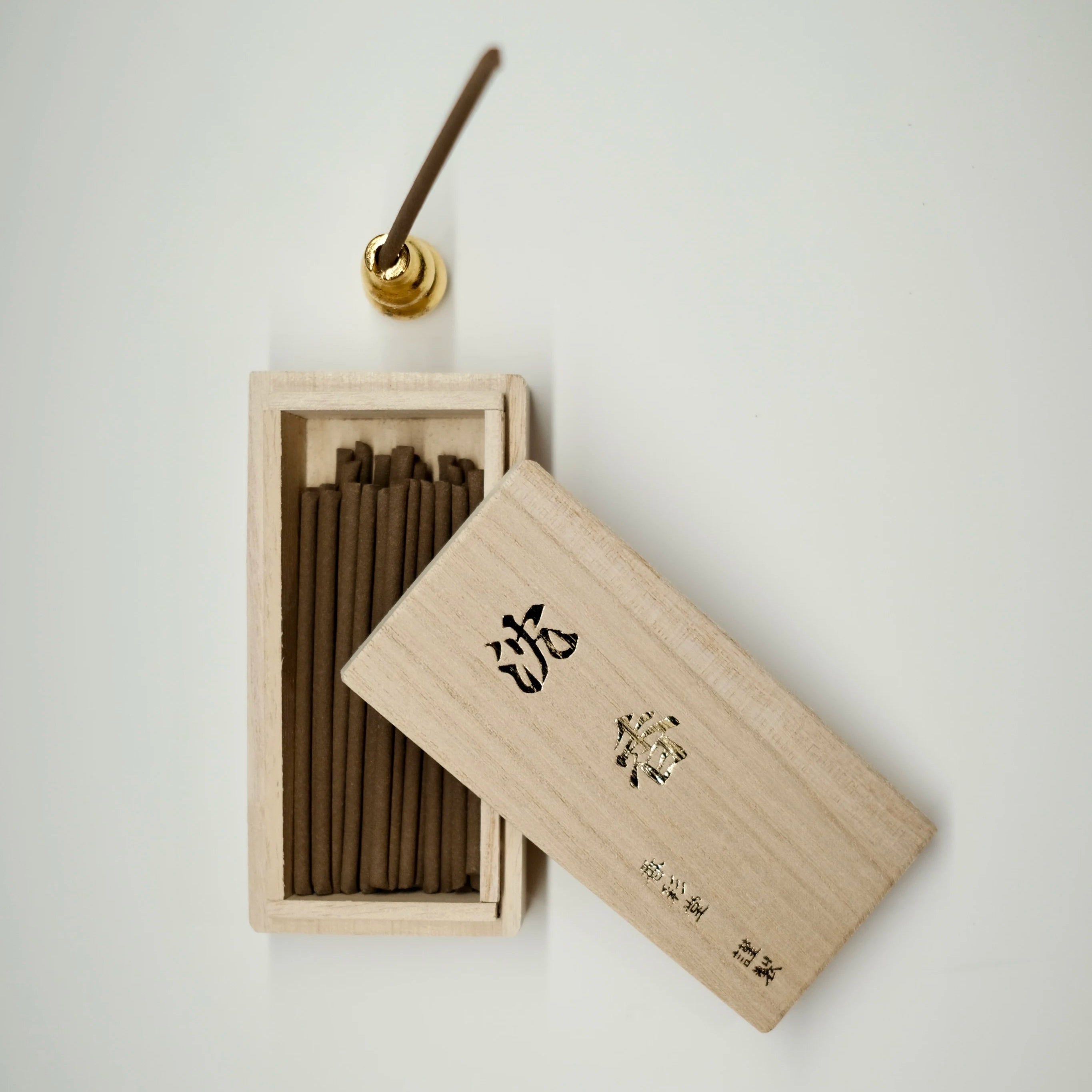 Wooden agarwood incense box with incense sticks on a light gray background