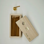 Wooden sandalwood incense box with incense sticks on a light gray background