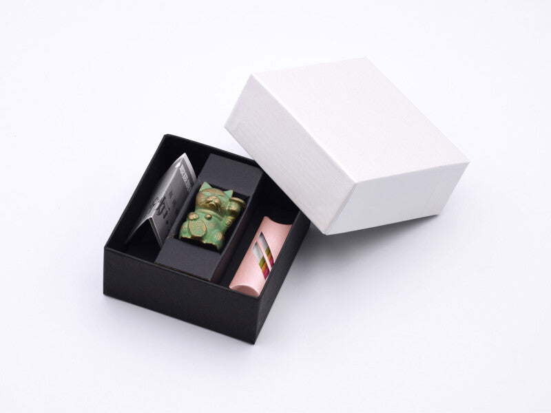 Open box containing a small green cat incense holder, pink package of incenses on a white background
