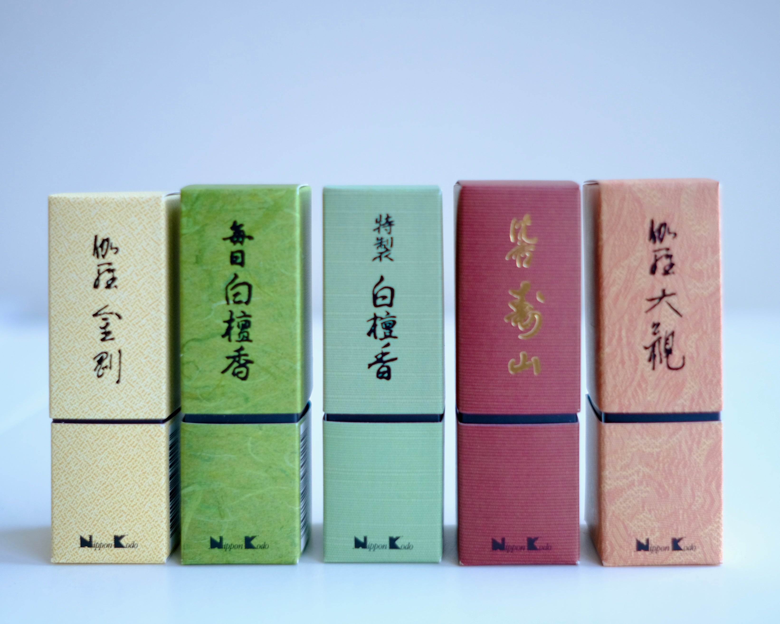 A lineup of five different boxes of Nippon Kodo Japanese incense, showcasing the brand's diverse collection. The colorful boxes, in shades of cream, green, red, and peach, feature elegant Japanese calligraphy and are arranged side-by-side against a white background.