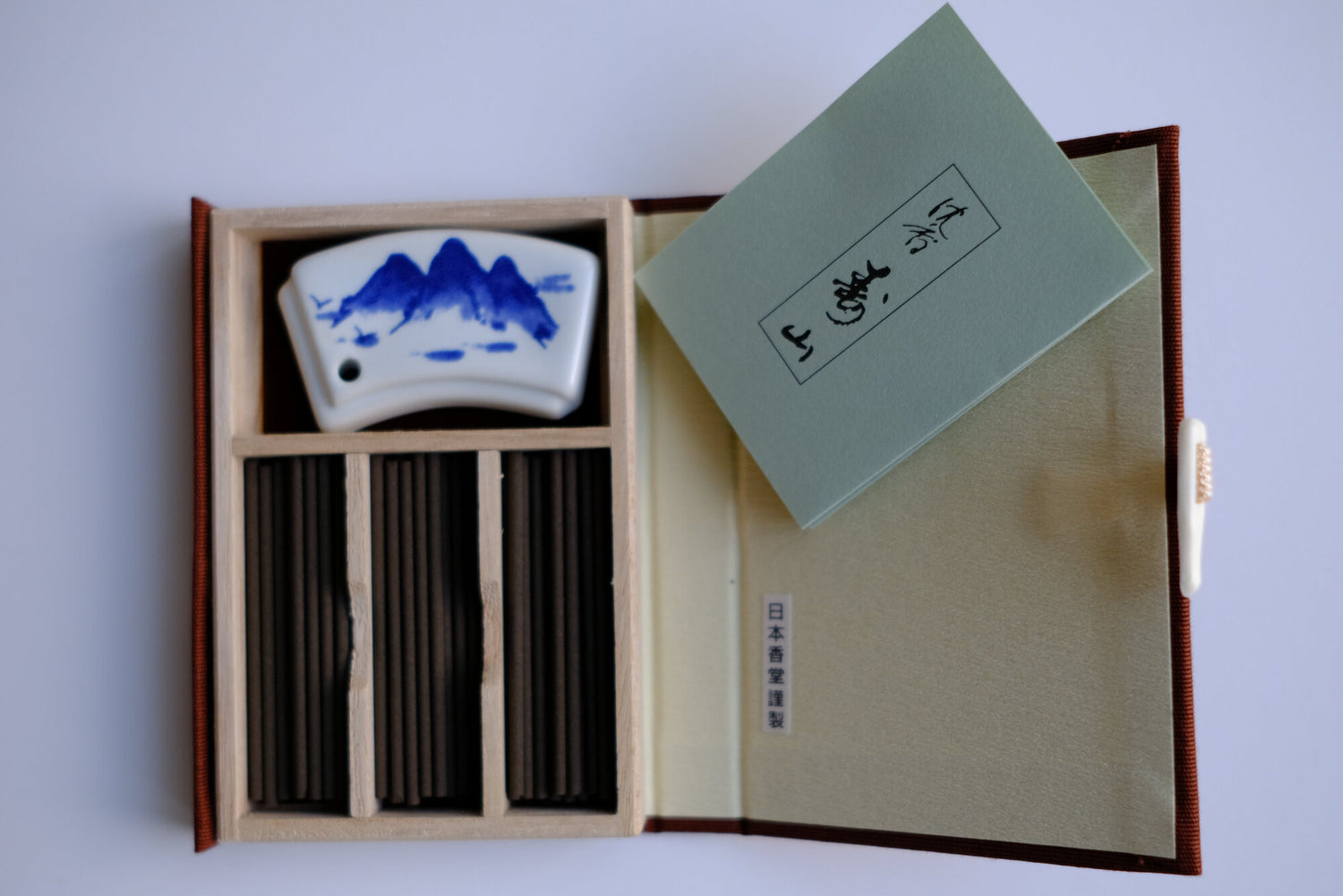 A product image of Jinkoh_Juzan__Nippon_Kodo, opened box with incense and ceramic holder, white background, for shop darabara.com