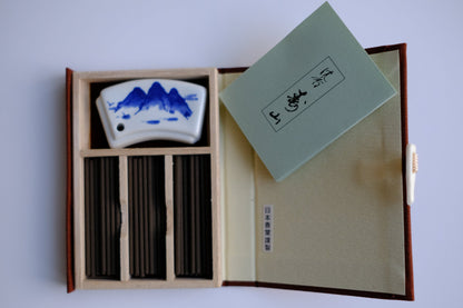 A product image of Jinkoh_Juzan__Nippon_Kodo, opened box with incense and ceramic holder, white background, for shop darabara.com