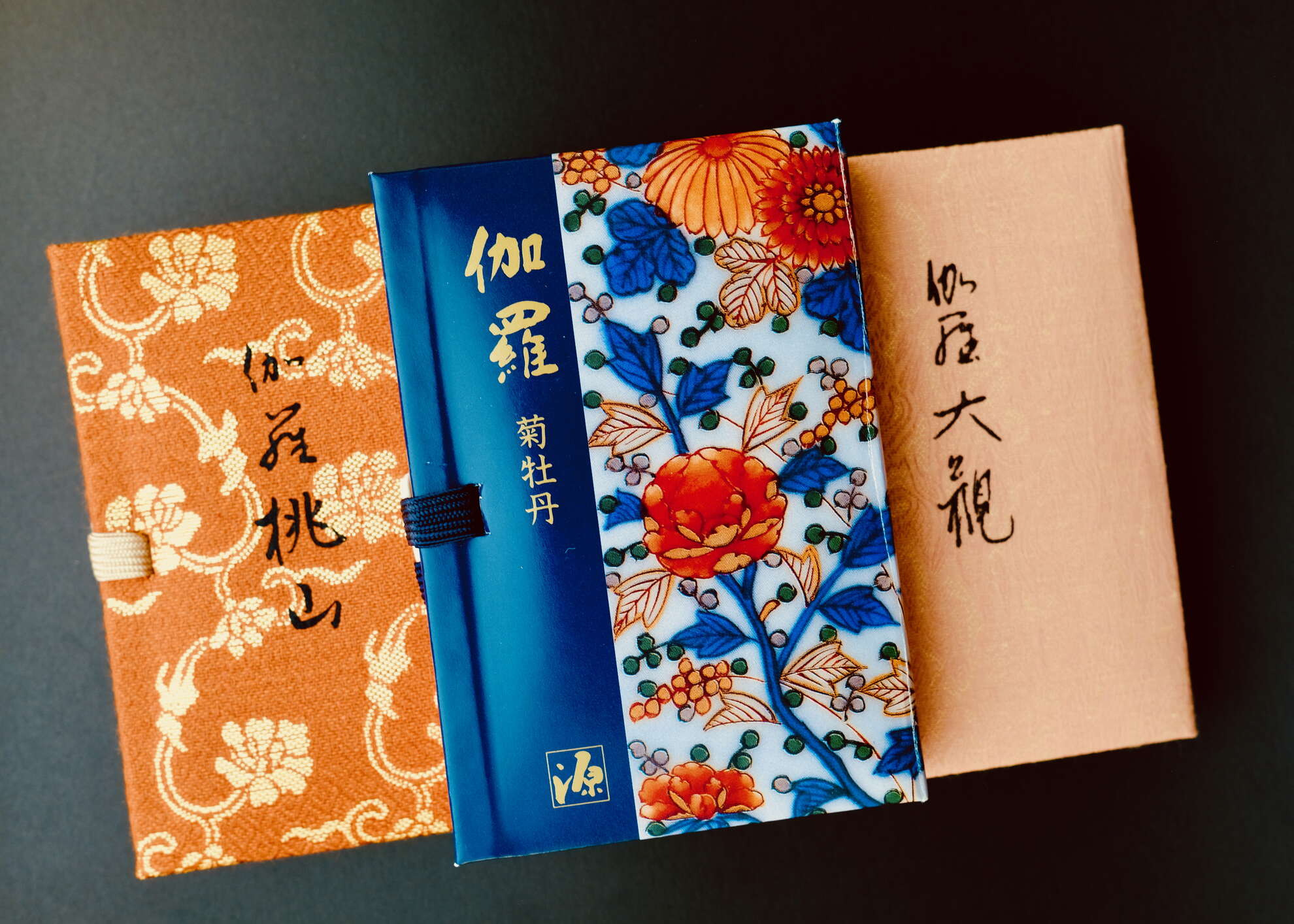 Three boxes of Nippon Kodo incenses laying on top of each other: Kyara Momoyama, Kyara Taikan, & Kyara Kiku botan.