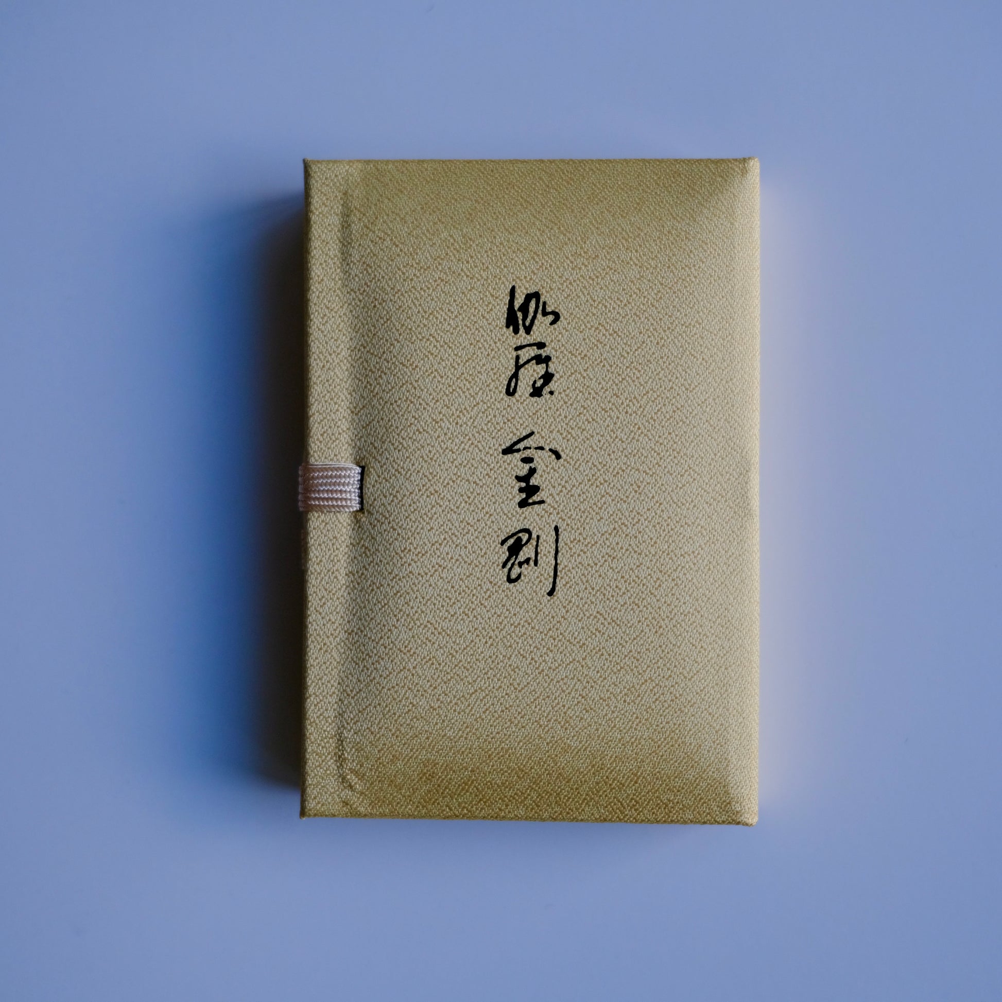 Nippon Kodo Kyara Kongo incense in its elegant, fabric-covered Paulownia wood box. The box is cream-colored with Japanese calligraphy, and a small purple ribbon is visible on the side. This premium Japanese incense is made from selected aloeswood and includes 60 sticks with a ceramic holder.