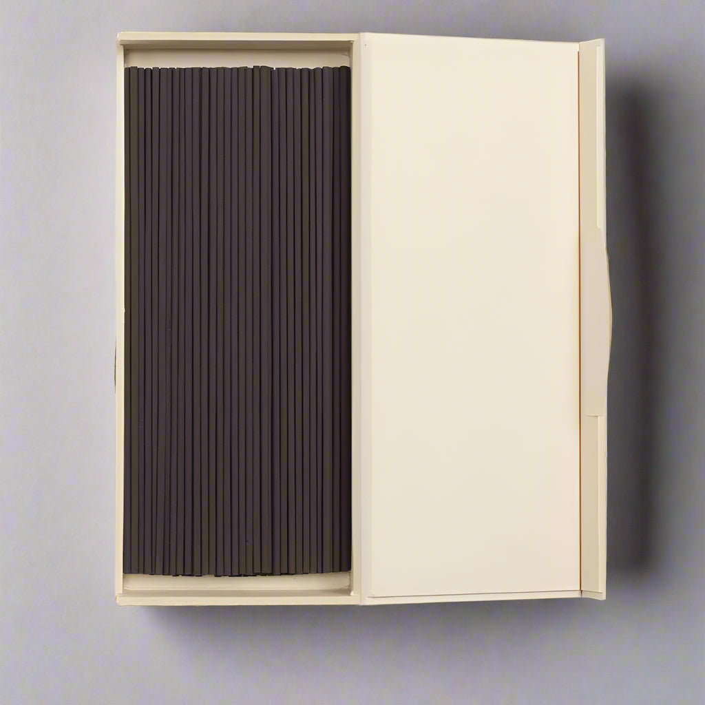 Beige box opened with black incense sticks on a white background