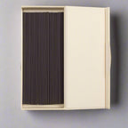 Beige box opened with black incense sticks on a white background