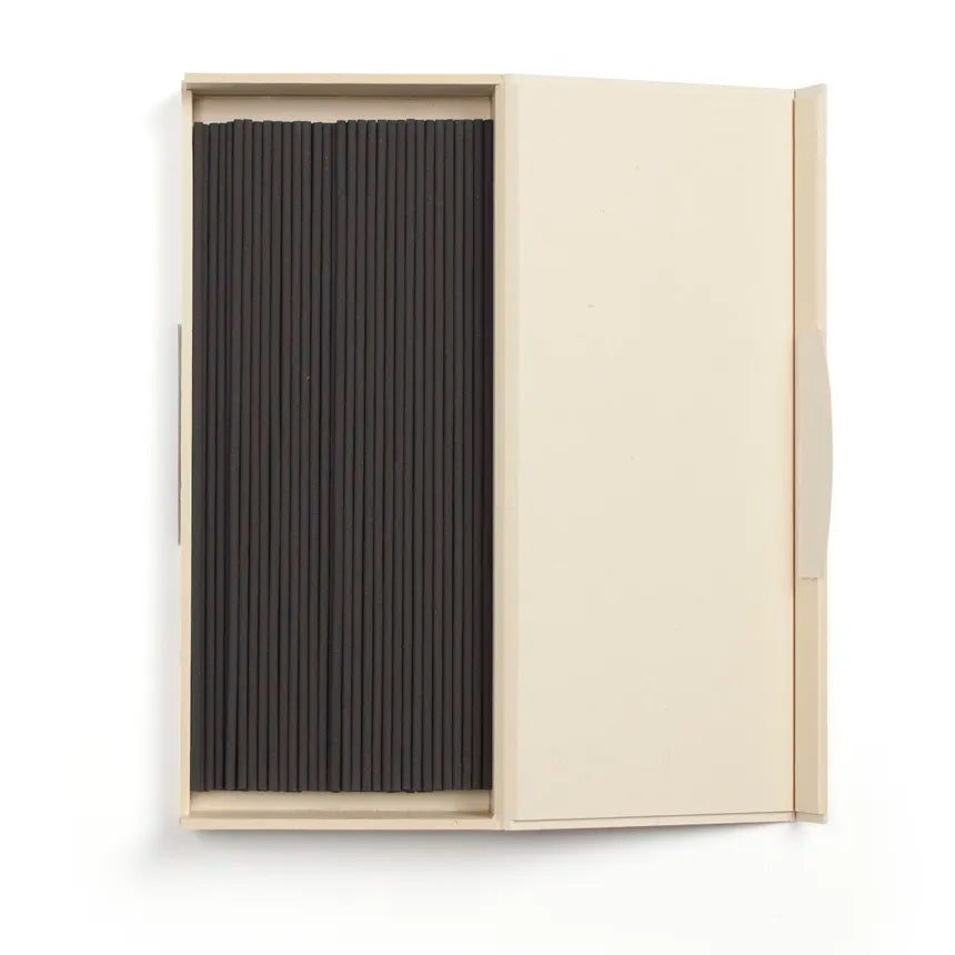 Black incense sticks in a beige box on a white background