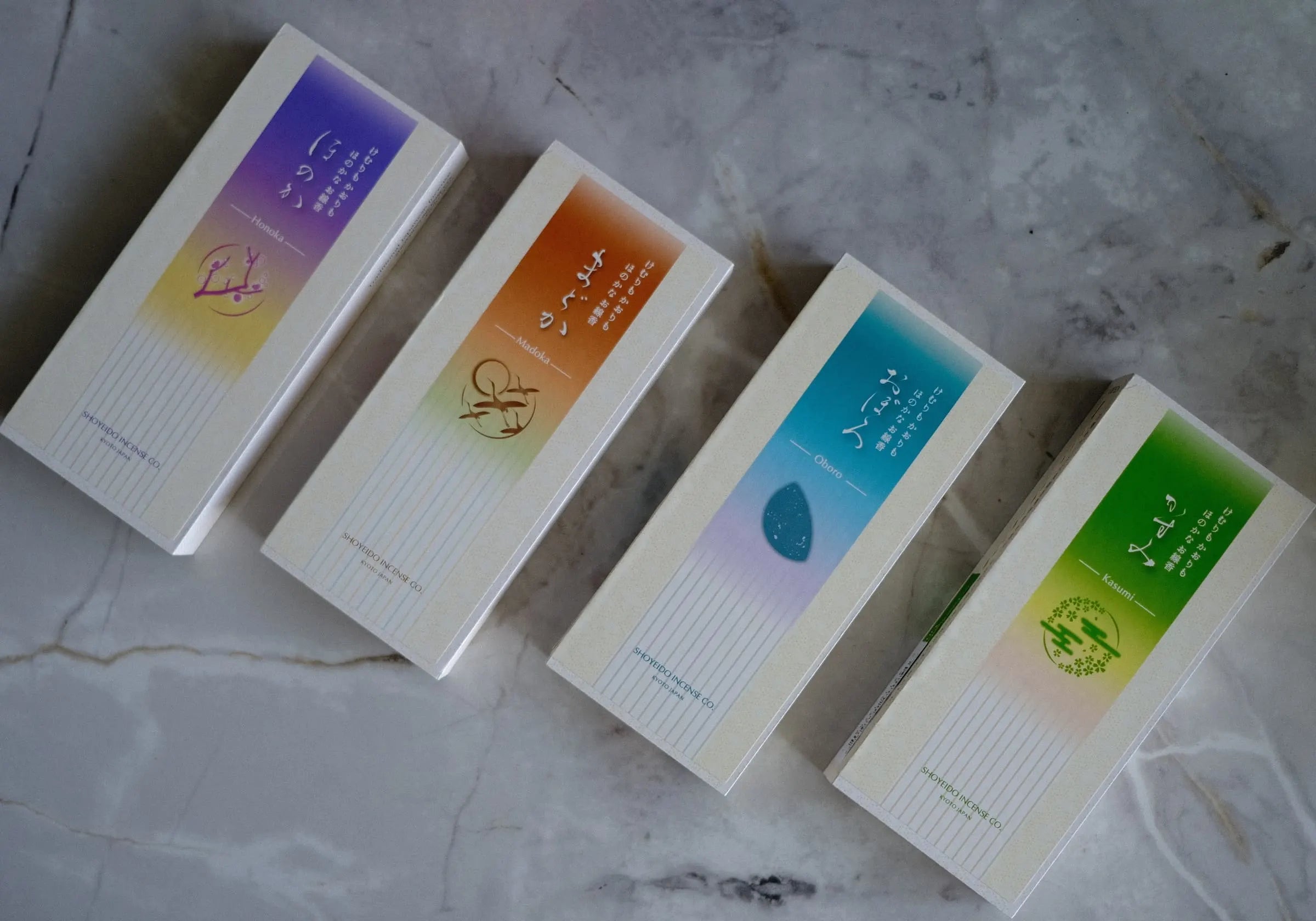Four small rectangular incense boxes with colorful labels on a marble surface, brand of Shoyeido