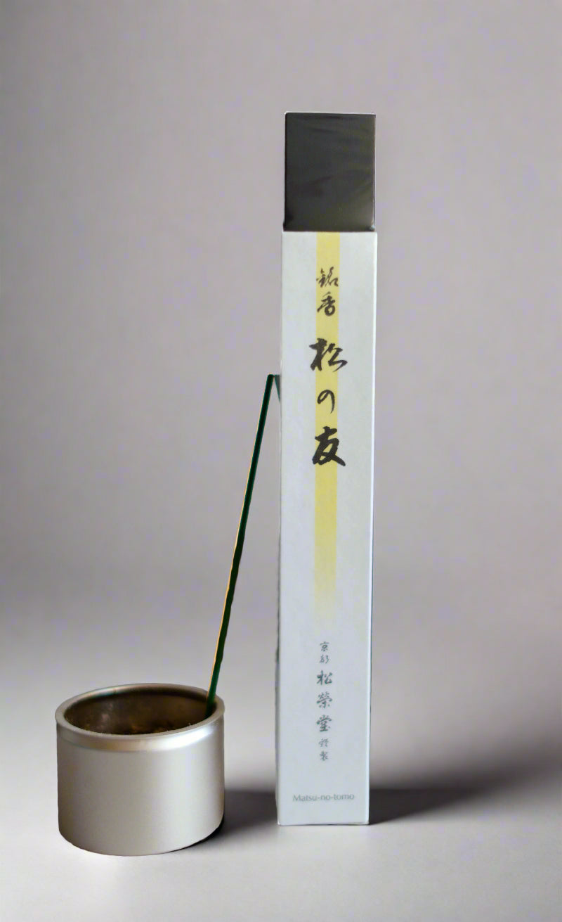A package of Shoyeido 'Matsu no Tomo' incense with a single incense stick burning in a holder.