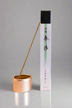 A package of Shunyou incense with a single incense stick burning, alongside a metal incense burner.