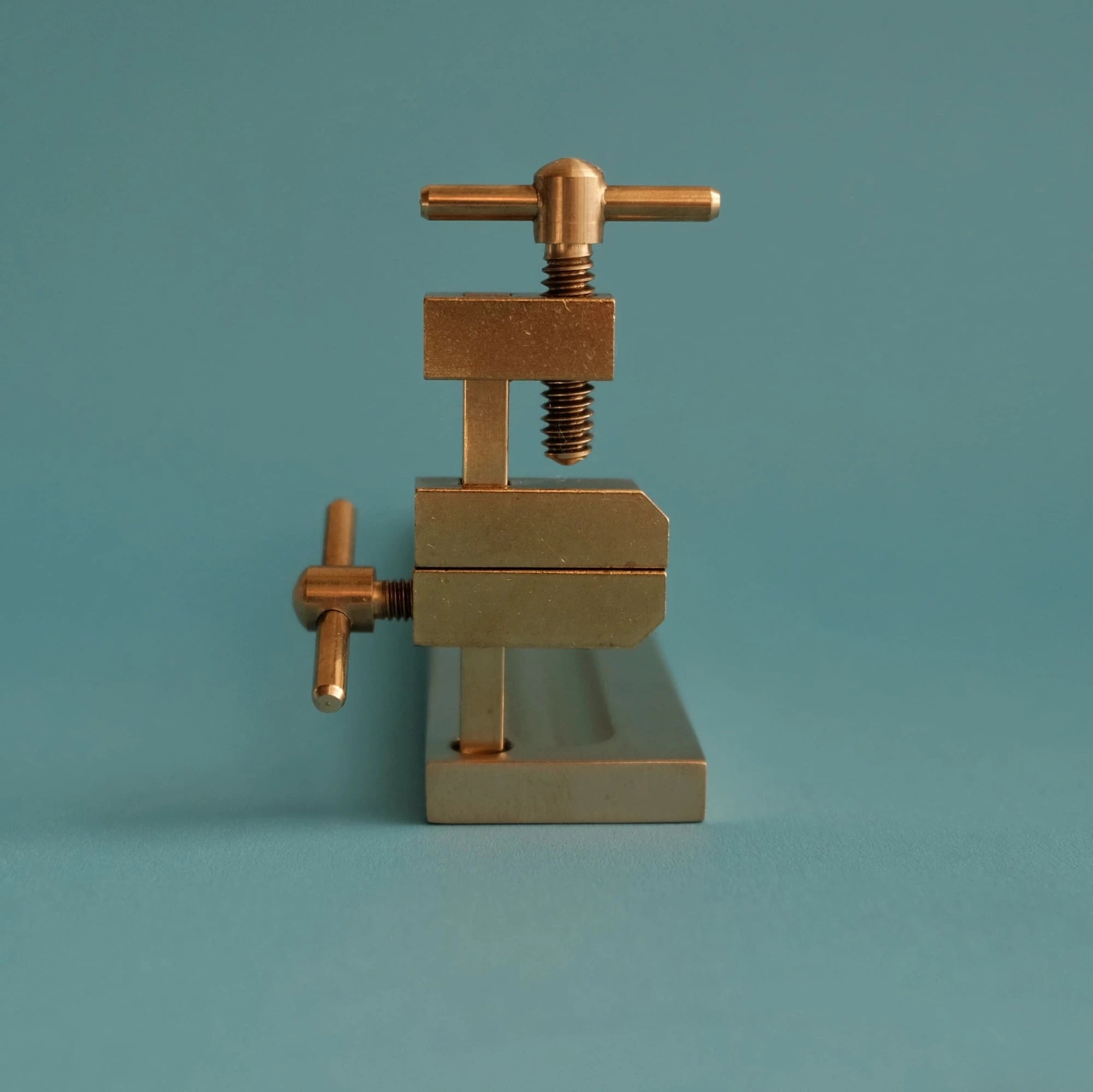 Brass clamp incense holder on a teal background